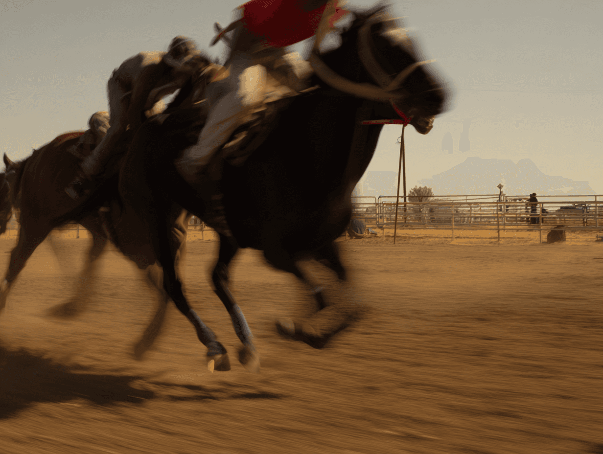 Two thoroughbred horses at full stride during a rural race, jockeys in red and white silks, golden hour dust