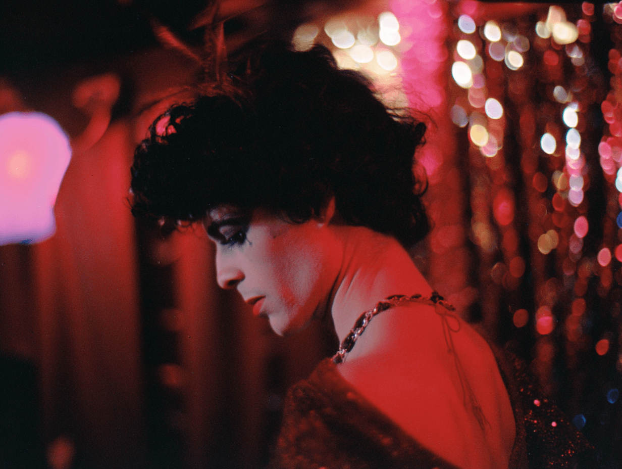 Dark-haired woman in profile inside a dimly lit nightclub, red light, magenta bokeh of fairy lights behind